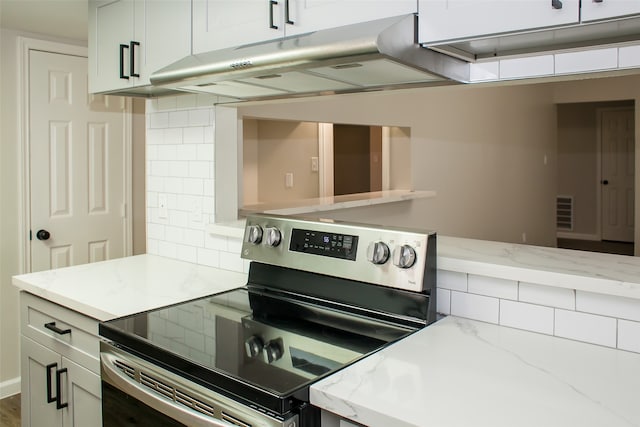 kitchen with light stone countertops, tasteful backsplash, white cabinetry, and stainless steel electric stove