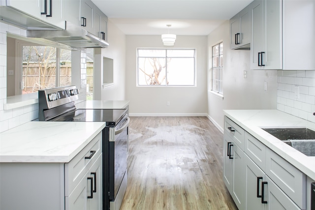 kitchen with backsplash, gray cabinetry, stainless steel range with electric cooktop, and light hardwood / wood-style flooring