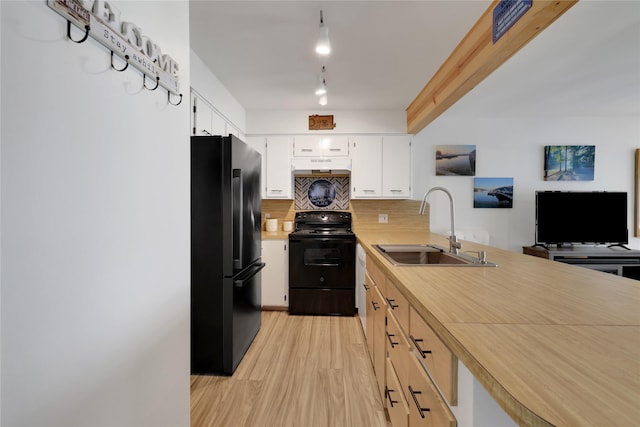 kitchen with tasteful backsplash, sink, white cabinets, black appliances, and light hardwood / wood-style flooring