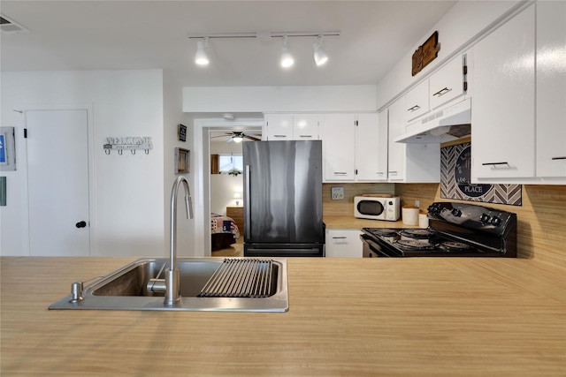 kitchen with sink, black electric range, stainless steel refrigerator, white cabinets, and backsplash