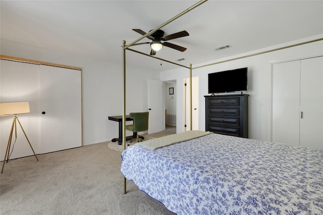 bedroom with ceiling fan, carpet flooring, and two closets