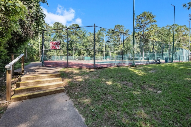 view of sport court with basketball hoop and a lawn