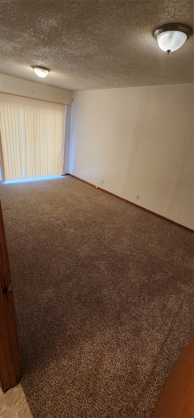 carpeted empty room featuring a textured ceiling