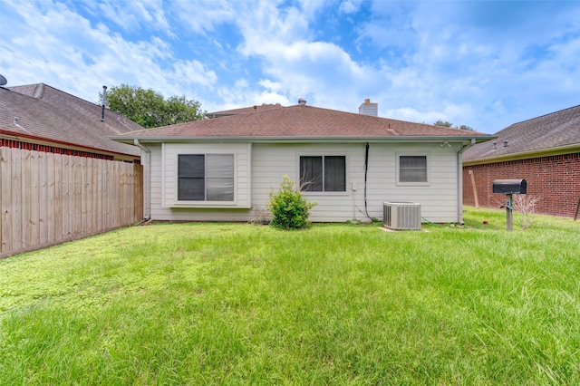 back of property with central AC and a yard