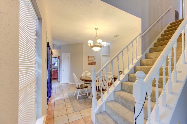 staircase featuring tile flooring, a notable chandelier, and a textured ceiling