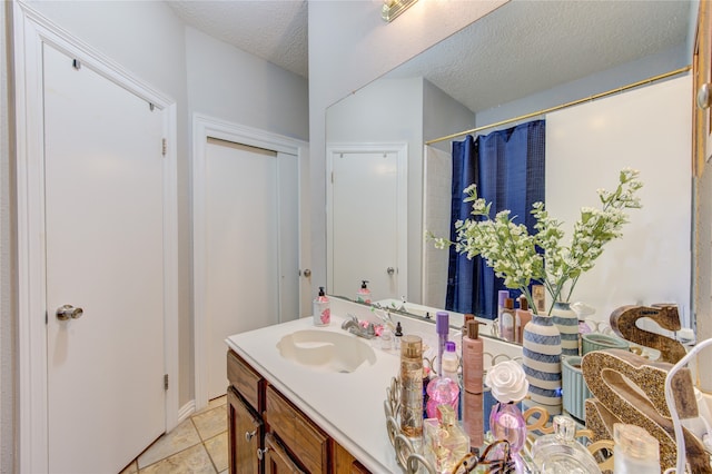 bathroom with tile flooring, vanity with extensive cabinet space, and a textured ceiling