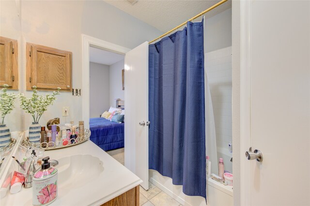 bathroom with tile flooring, vanity, shower / bath combo, and a textured ceiling