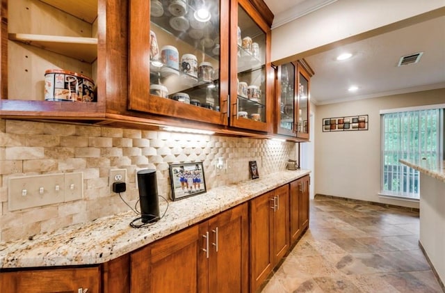 kitchen with backsplash, light stone countertops, light tile floors, and ornamental molding