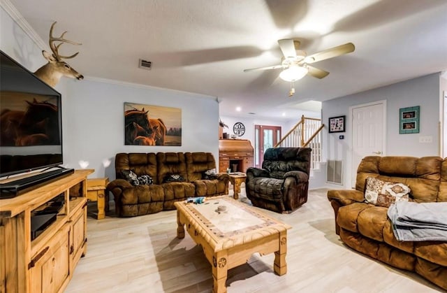 living room with ceiling fan, crown molding, and light wood-type flooring