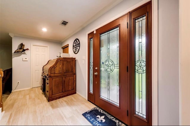 foyer with crown molding and light hardwood / wood-style floors