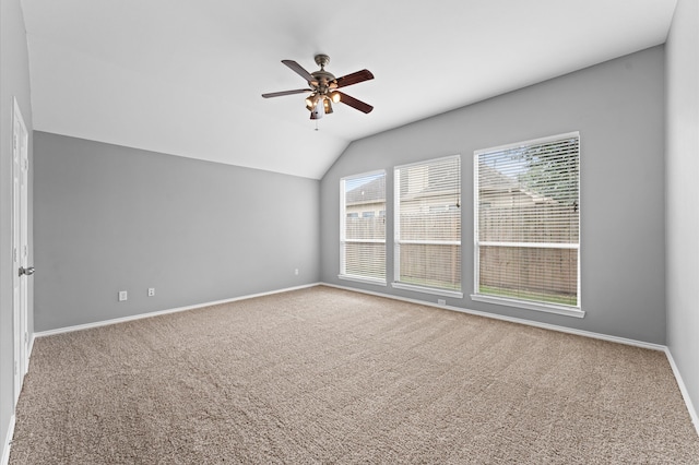 carpeted spare room featuring vaulted ceiling and ceiling fan