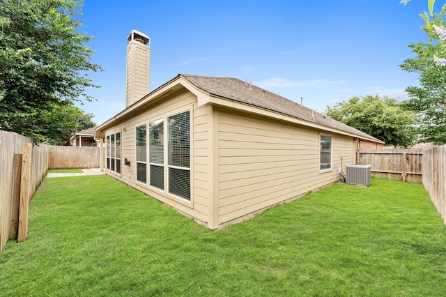 rear view of property featuring central AC and a lawn