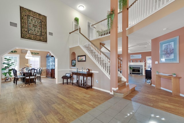 foyer entrance with a towering ceiling, stairs, visible vents, and wood finished floors