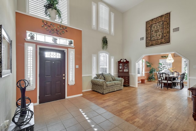 entryway featuring arched walkways, visible vents, baseboards, and wood finished floors