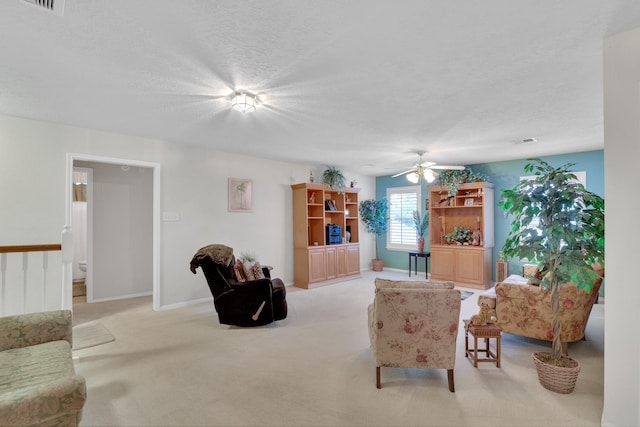 living room featuring visible vents, light carpet, ceiling fan, a textured ceiling, and baseboards