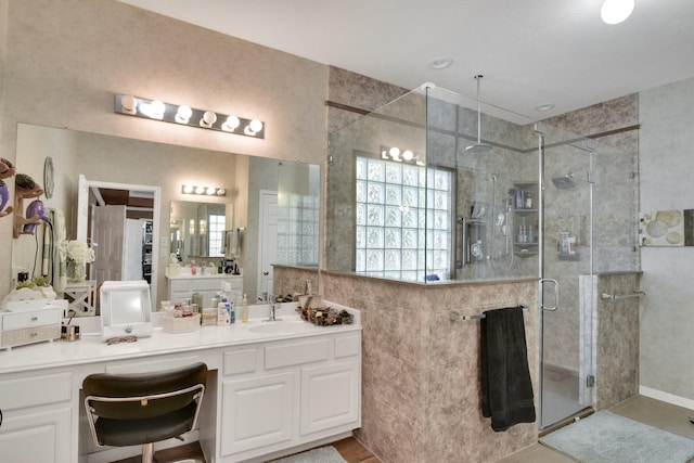 bathroom featuring vanity, a shower stall, and tile walls