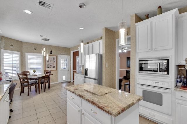 kitchen featuring white cabinetry, a kitchen island, visible vents, and stainless steel appliances