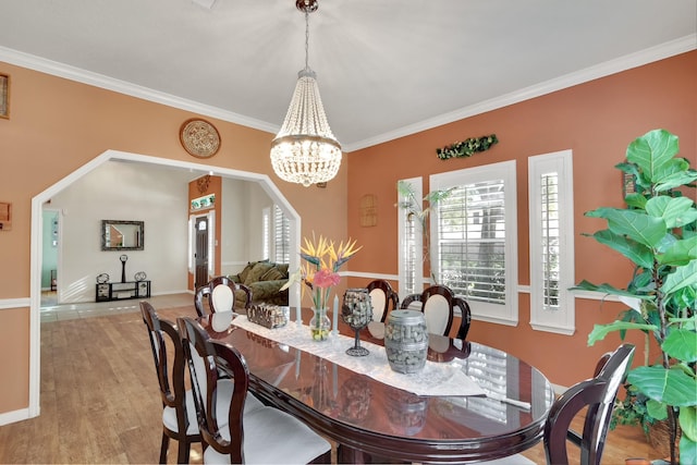 dining area featuring light wood finished floors, a chandelier, and crown molding