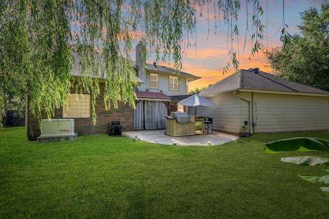 back house at dusk featuring a yard and a patio area