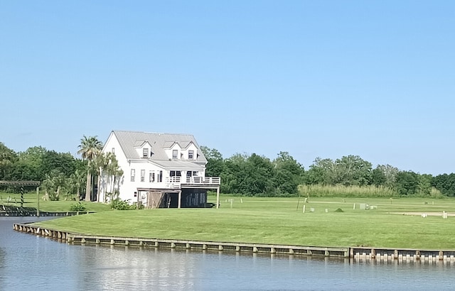 rear view of property featuring a water view and a lawn