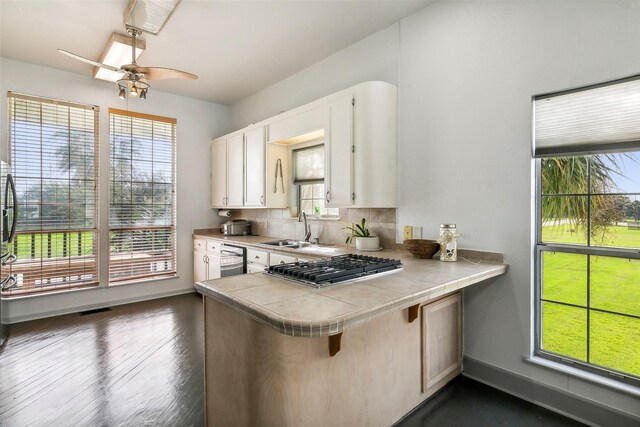 kitchen with white cabinetry, kitchen peninsula, tile counters, and sink