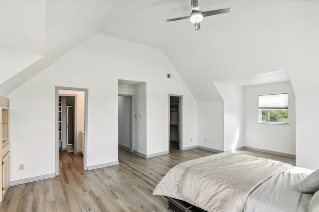 bedroom featuring a spacious closet, light hardwood / wood-style floors, a closet, vaulted ceiling, and ceiling fan