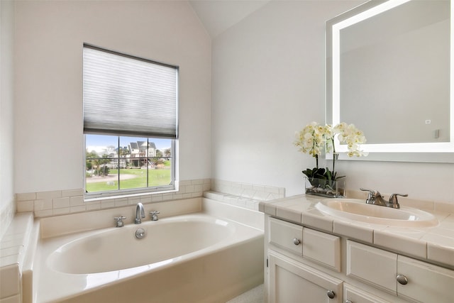 bathroom with vanity, vaulted ceiling, and a washtub