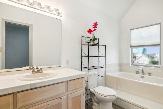 bathroom with toilet, vanity, vaulted ceiling, and a bathtub