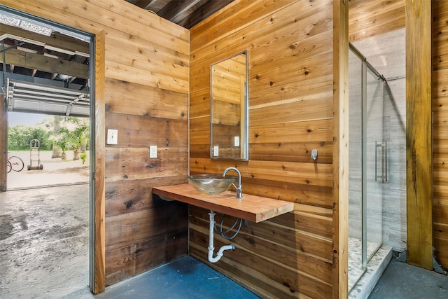 full bathroom with wood walls, a shower stall, and a sink