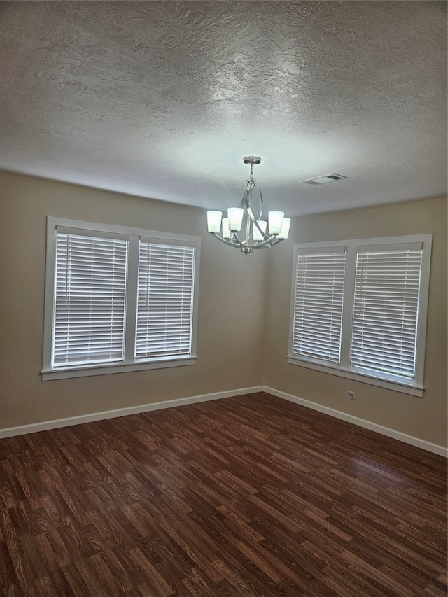 unfurnished room with a chandelier, a textured ceiling, and dark wood-type flooring