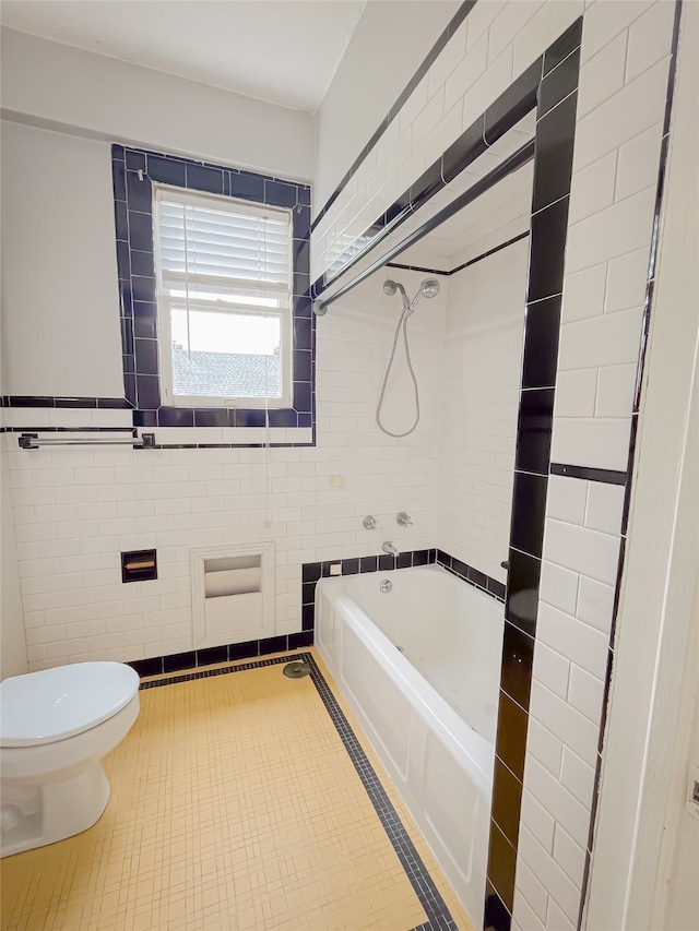 bathroom with tiled shower / bath combo, tile walls, toilet, and tile floors