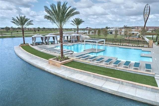 view of pool featuring a lawn, a patio, and a water view