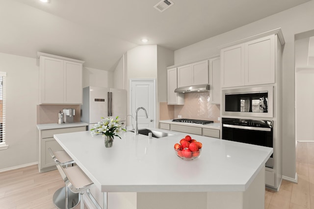 kitchen with a kitchen island with sink, sink, white cabinetry, high end white fridge, and oven