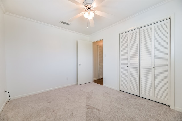 unfurnished bedroom featuring ceiling fan, ornamental molding, light carpet, and a closet