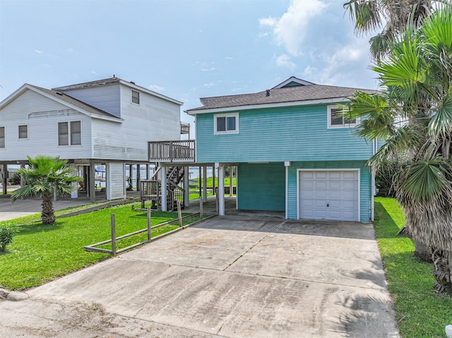 raised beach house featuring a garage, a deck, and a front yard