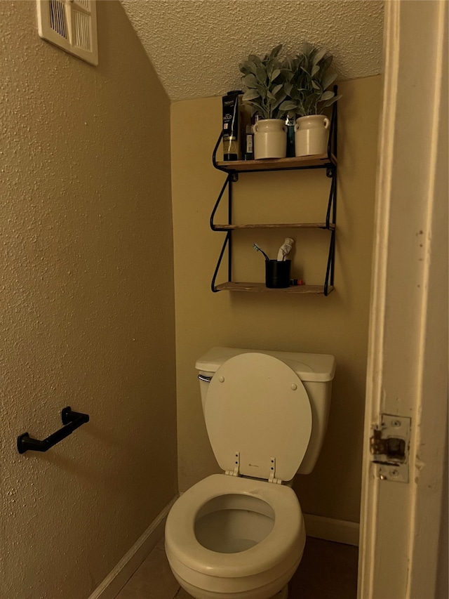 bathroom featuring tile flooring, toilet, a textured ceiling, and lofted ceiling