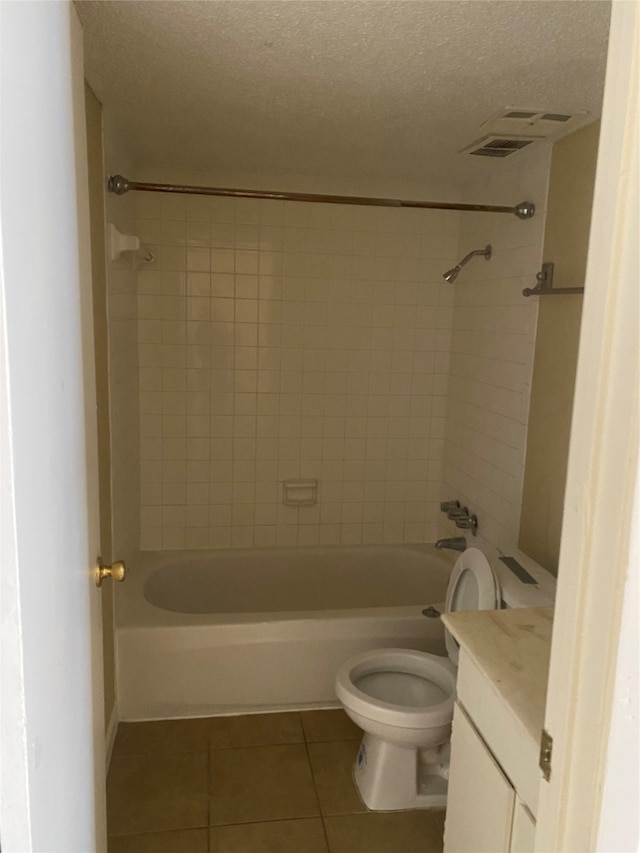 full bathroom with tiled shower / bath combo, a textured ceiling, toilet, and tile floors