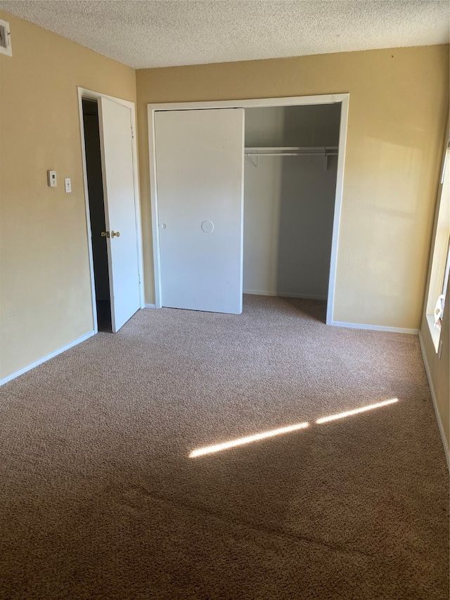 unfurnished bedroom featuring carpet, a closet, and a textured ceiling