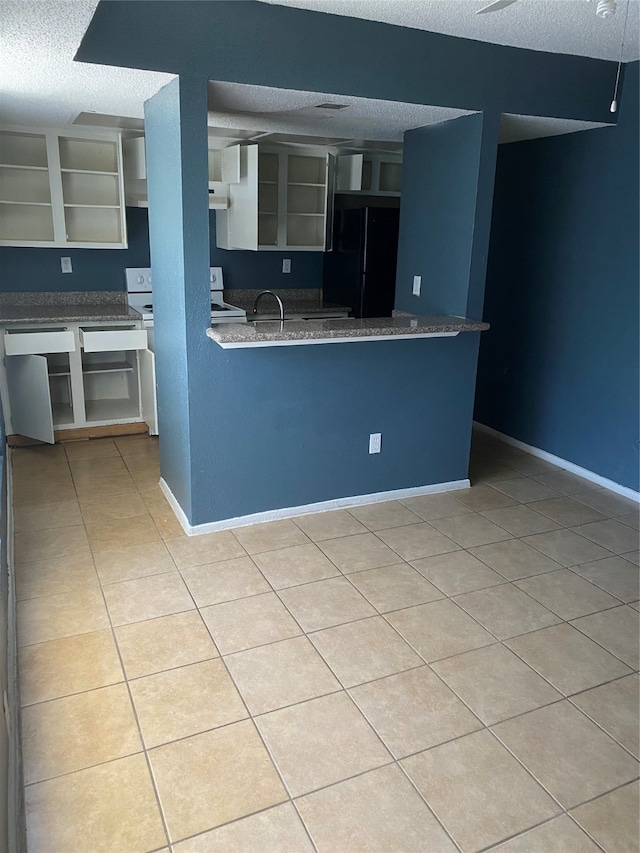 kitchen with black fridge, a textured ceiling, white electric stove, and light tile floors