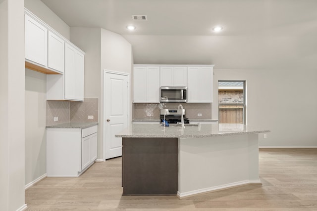 kitchen featuring white cabinets, light wood-type flooring, appliances with stainless steel finishes, and a kitchen island with sink