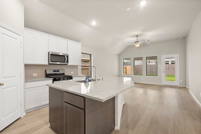 kitchen featuring stainless steel appliances, vaulted ceiling, white cabinets, sink, and light hardwood / wood-style flooring