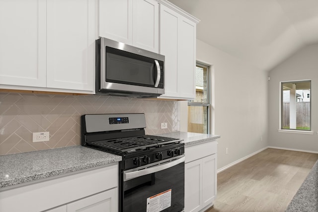 kitchen featuring stainless steel appliances, light hardwood / wood-style floors, white cabinets, decorative backsplash, and light stone countertops