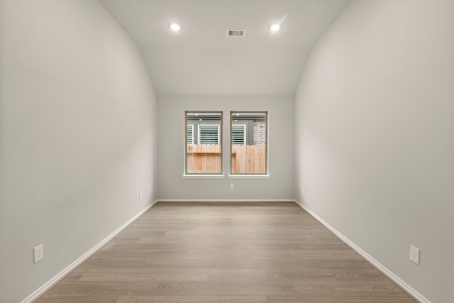 unfurnished room with light wood-type flooring and lofted ceiling