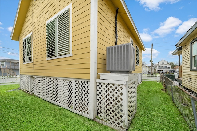 view of side of home featuring cooling unit and a lawn