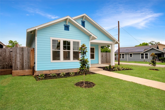 view of front of property with a front yard and solar panels