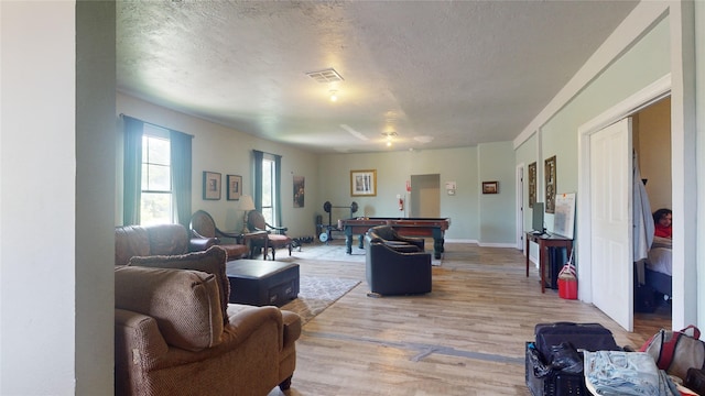 living room with a textured ceiling, light hardwood / wood-style floors, and pool table