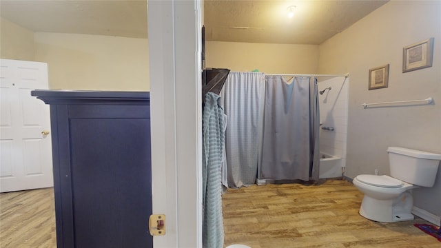 bathroom featuring shower / tub combo, wood-type flooring, and toilet