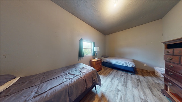 bedroom with lofted ceiling and light wood-type flooring