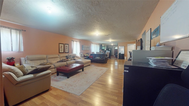 living room with plenty of natural light, light wood-type flooring, and a textured ceiling