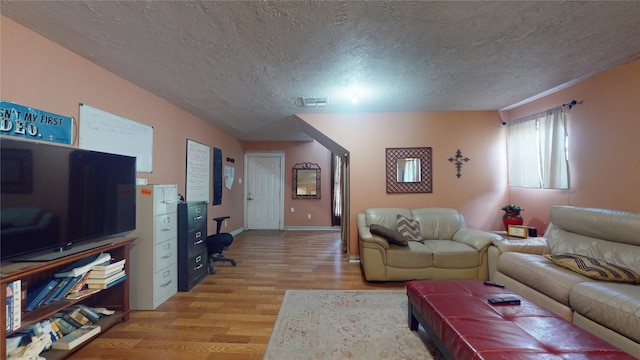 living room with a textured ceiling and light wood-type flooring